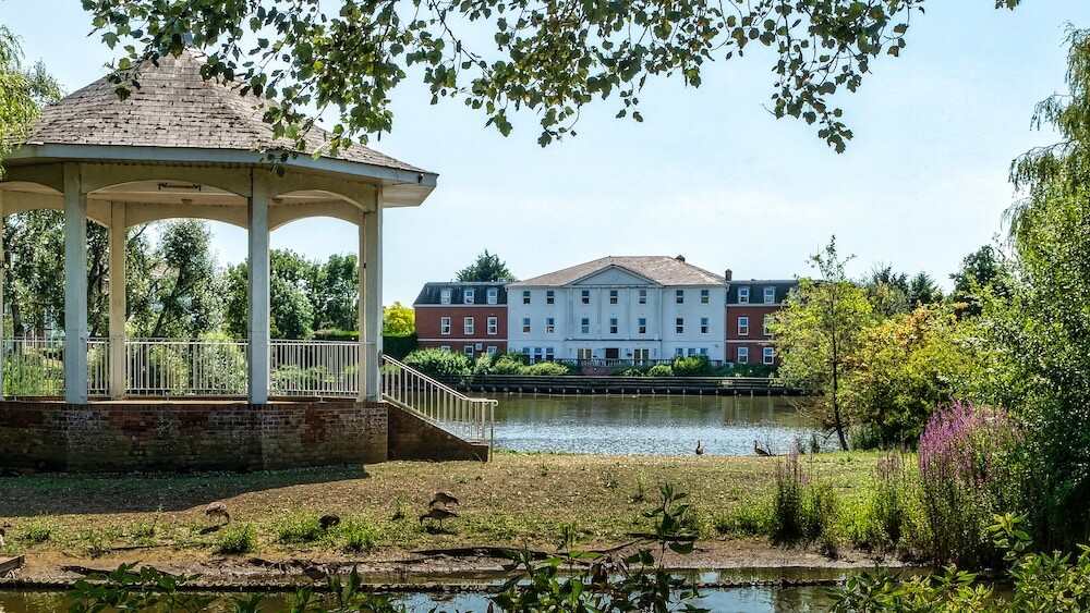 View of the care home from the lake perspective, with a beautiful bandstand prominently in the foreground.