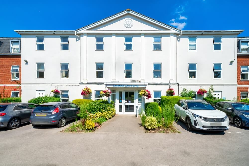 Entry view of a care home with an entry door and a car park in front.